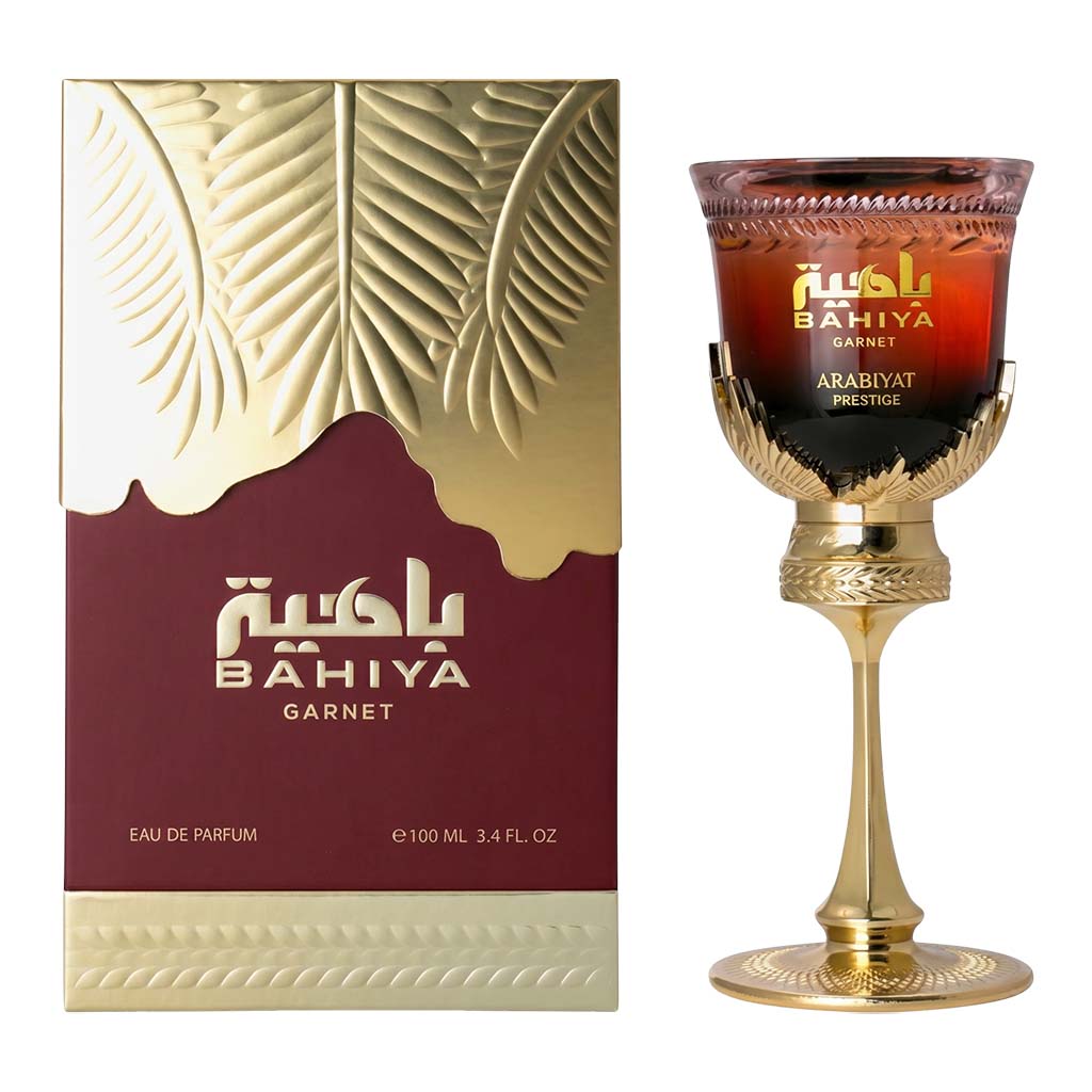 Bahiya Garnet perfume packaging and a decorative glass with gold accents.