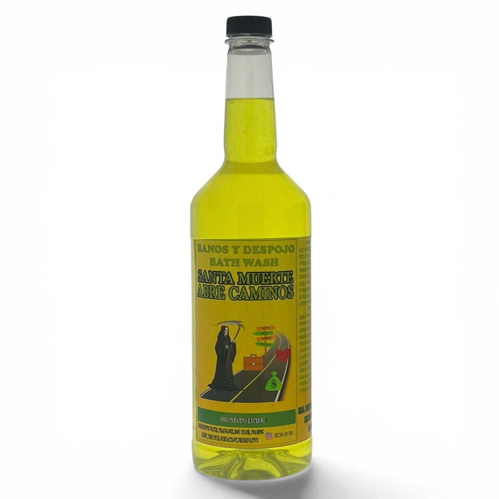 A clear glass bottle of Santa Muerte Arre Camino bath wash filled with yellow liquid, featuring a black cap and a yellow label with a grim reaper illustration, set against a plain white background.