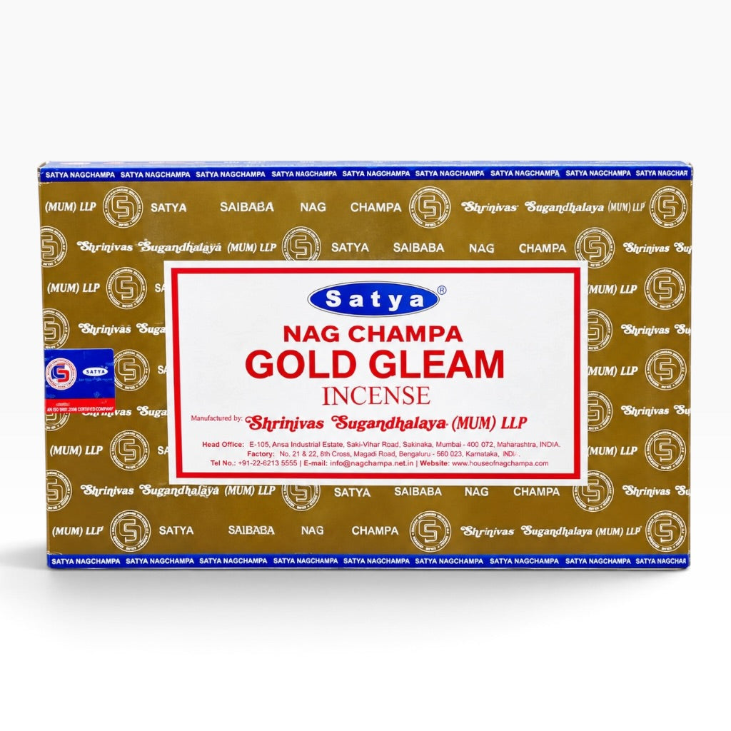A rectangular box of Satya Nag Champa Gold Gleam Incense on a plain white background. The box features a gold patterned background with repeated Satya logos, a blue band at the top and bottom, and a large white central label with red and blue text.