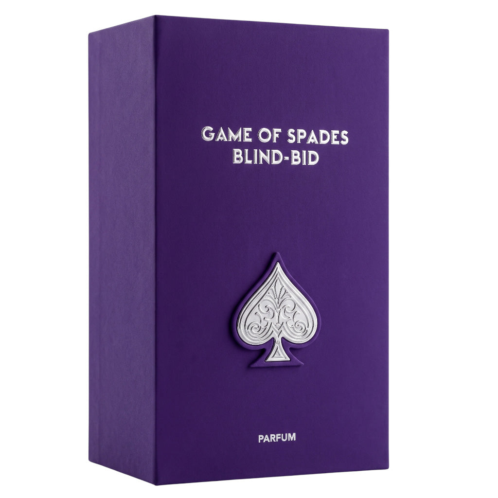 Purple rectangular box with white text reading 'GAME OF SPADES BLIND-BID' and 'PARFUM', featuring a raised silver spade emblem on the front, shown on a white background.
